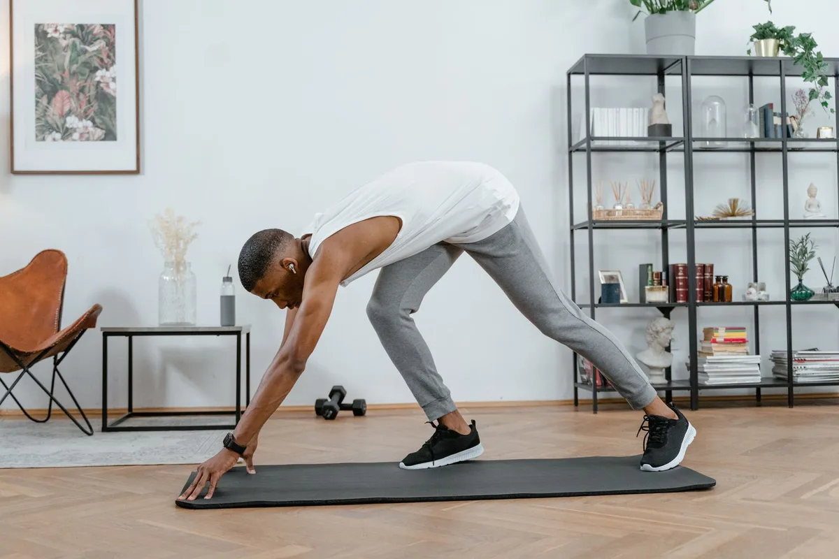 A man stretching on an exercise mat at home.