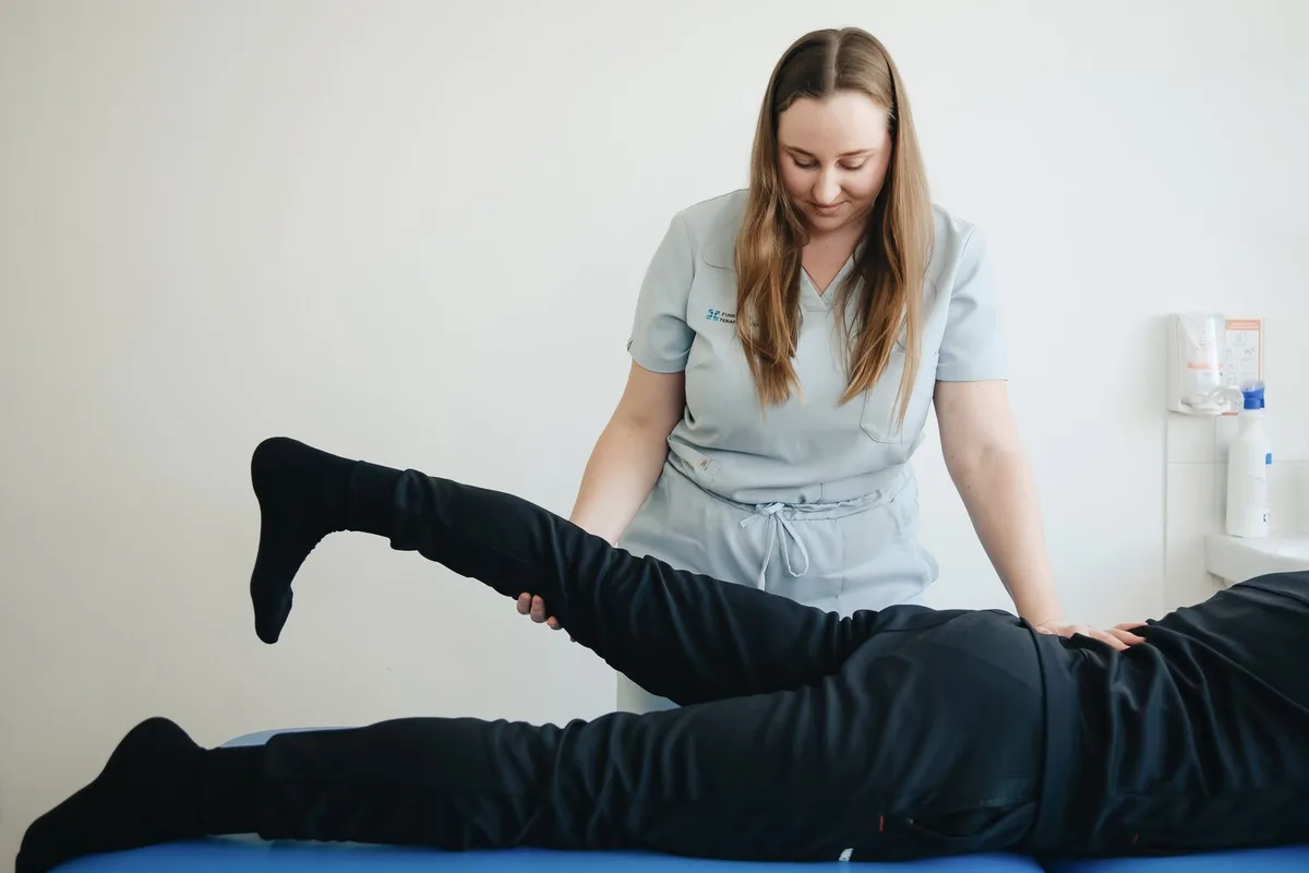 A physical therapist assessing a patient’s leg movement.