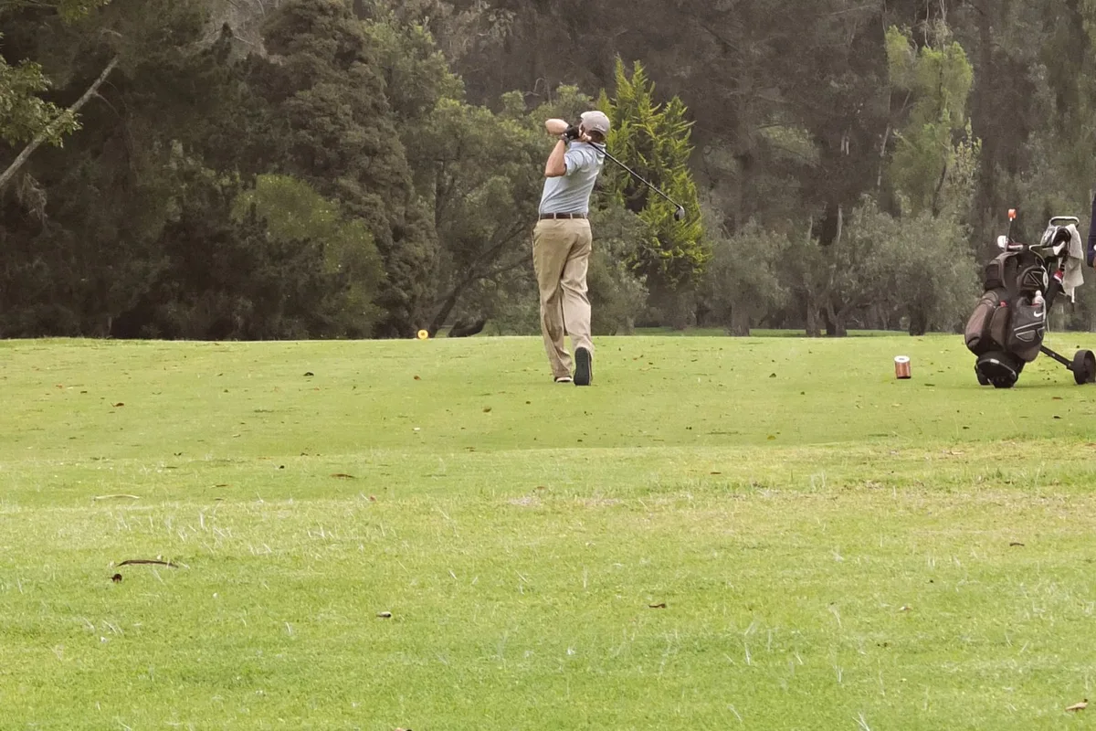 A golfer practicing a swing on a green golf course.