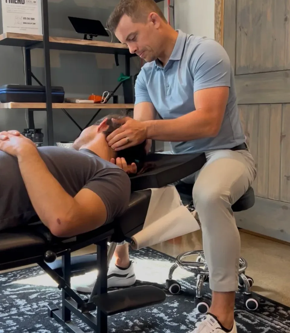 Dr. Ethan Coghill providing hands-on neck care to a patient.